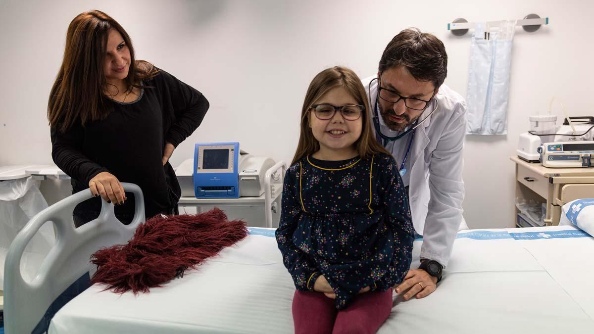 Vall d’Hebron realiza un triple trasplante a una niña por primera vez en España. En la foto, Iria con su madre y uno de sus médicos.