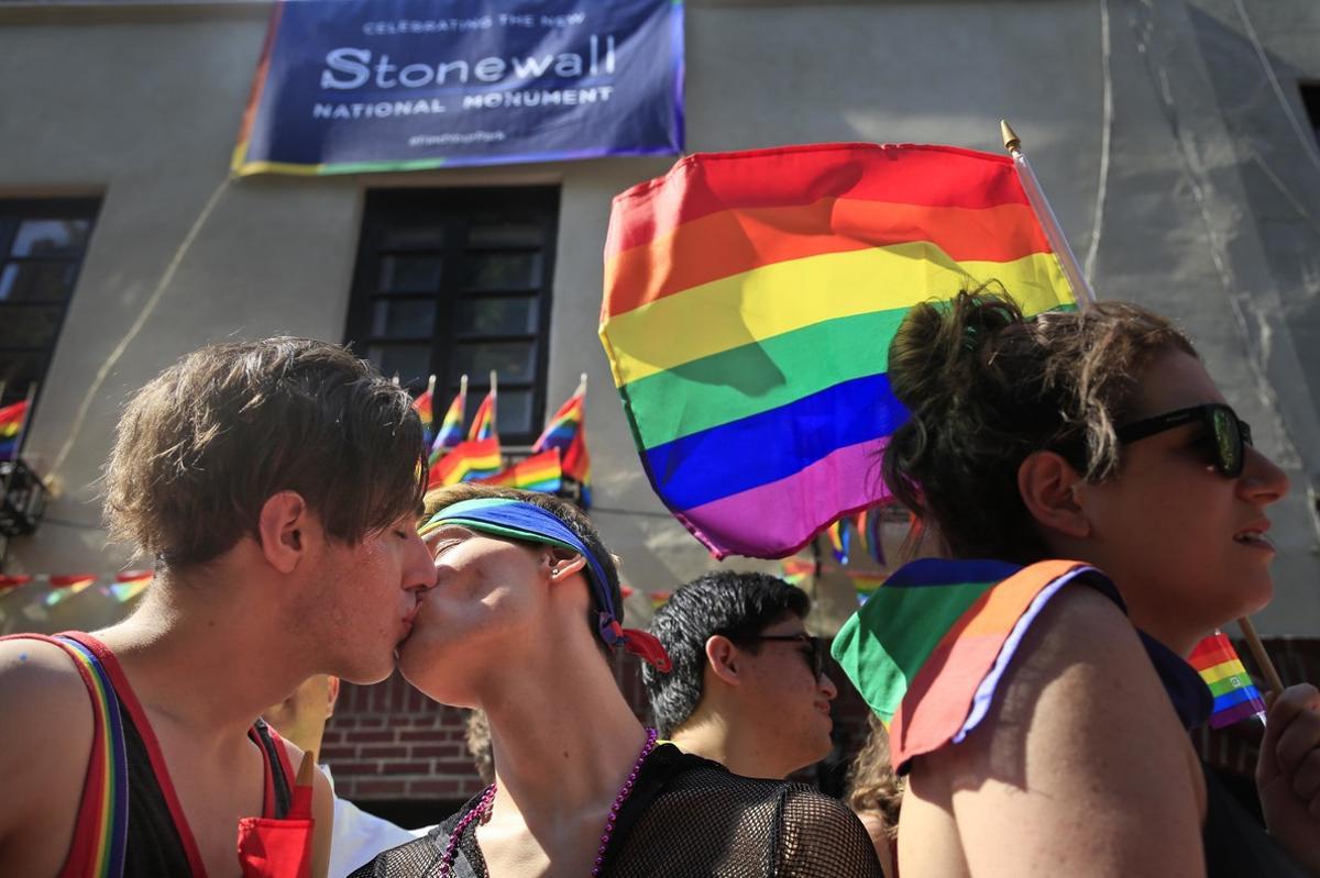 Una pareja de gais se besan frente al Stonewall, declarado monumento nacional, durante la Pride Parade de Nueva York.