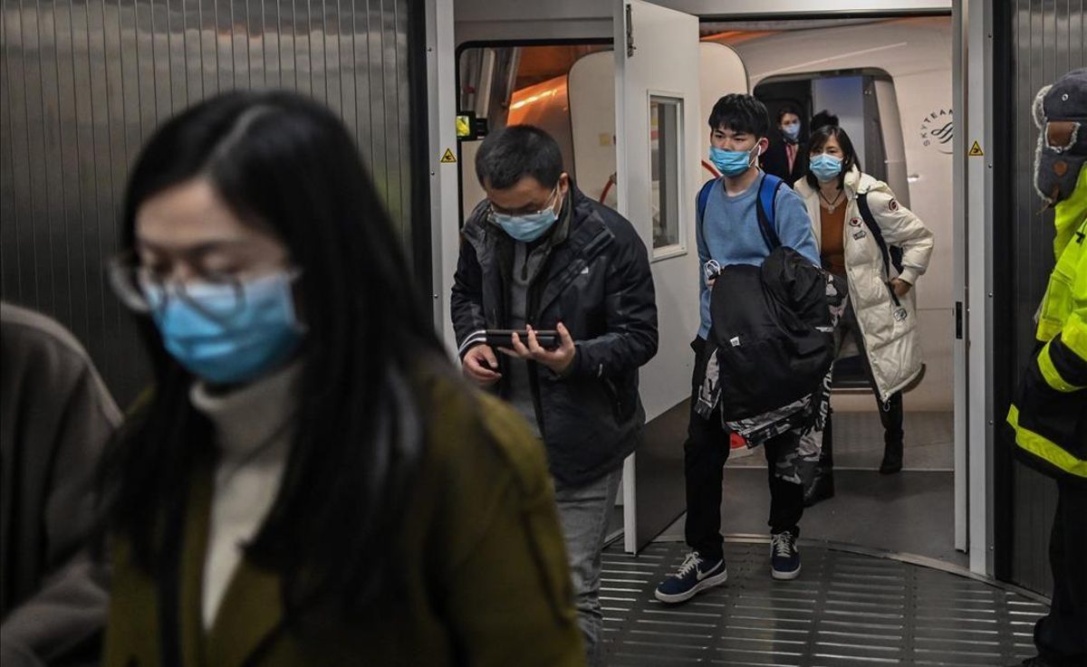 Pasajeros con mascarilla salen de un avión, tras aterrizar en el aeropuerto de Wuhan. Pasajeros con mascarilla salen de un avión, tras aterrizar en el aeropuerto de Wuhan.