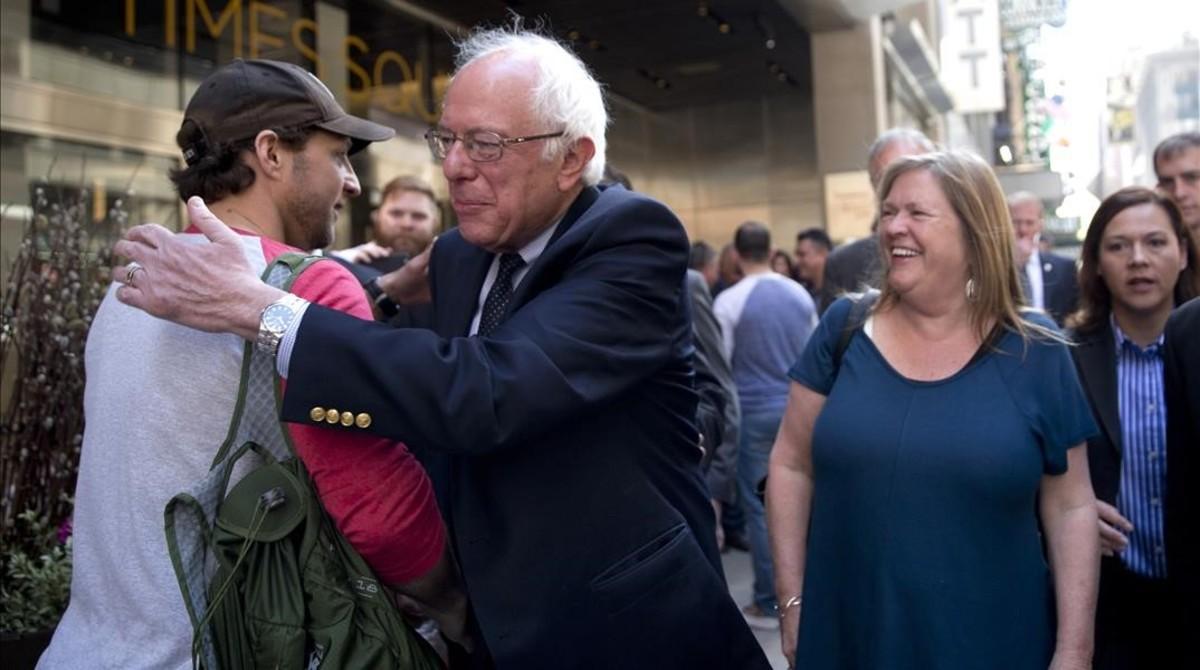 Sanders, acompañado por su mujer, abraza a un peatón de paseo por Times Squares, este martes.