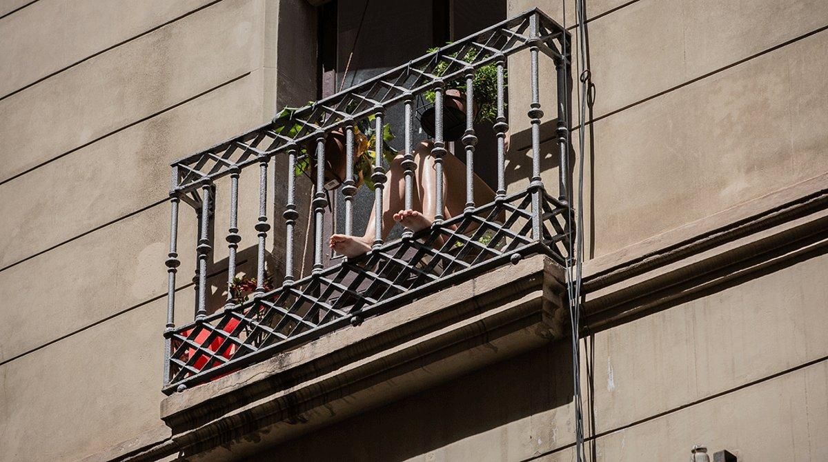 Una mujer disfruta del sol desde su balcón, en un edificio de Barcelona, el 12 de mayo. Una mujer disfruta del sol desde su balcón, en un edificio de Barcelona, el 12 de mayo.