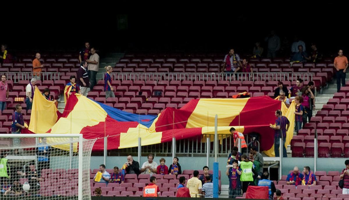 Unos aficionados despliegan una bandera antes del partido.