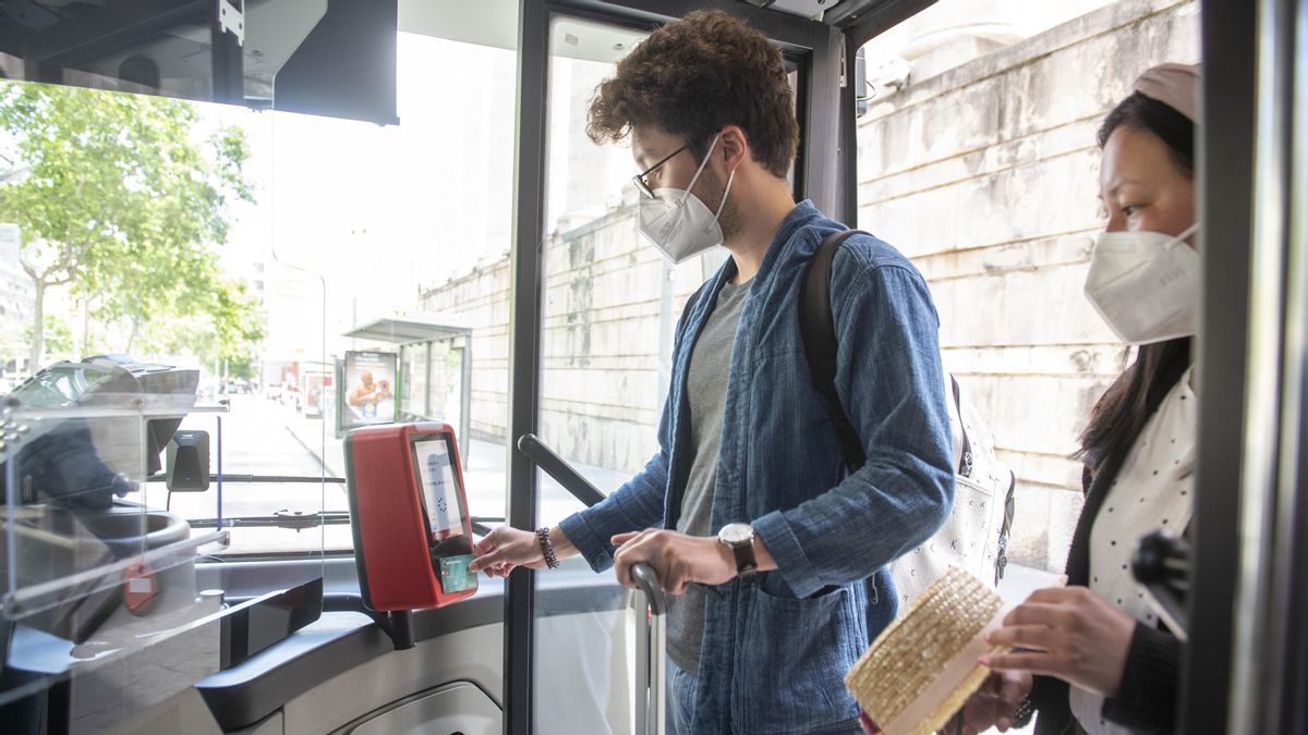 Una pareja de turistas asiáticos paga con tarjeta de crédito el billete de 2,40 euros de la línea 46 de bus al aeropuerto Una pareja de turistas asiáticos paga con tarjeta de crédito el billete de 2,40 euros de la línea 46 de bus al aeropuerto