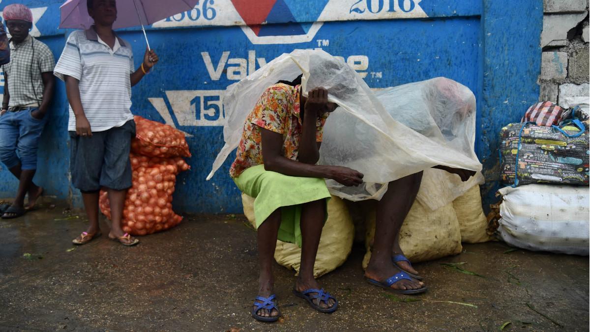Unas mujeres se protegen de la lluvia con un plástico en la capital de Haití, Port-au-Prince. 