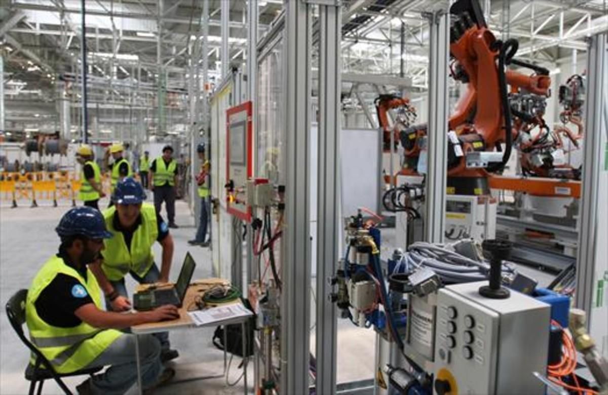 Operarios de la fábrica de Seat en Martorell, trabajando con brazos robotizados. Operarios de la fábrica de Seat en Martorell, trabajando con brazos robotizados.