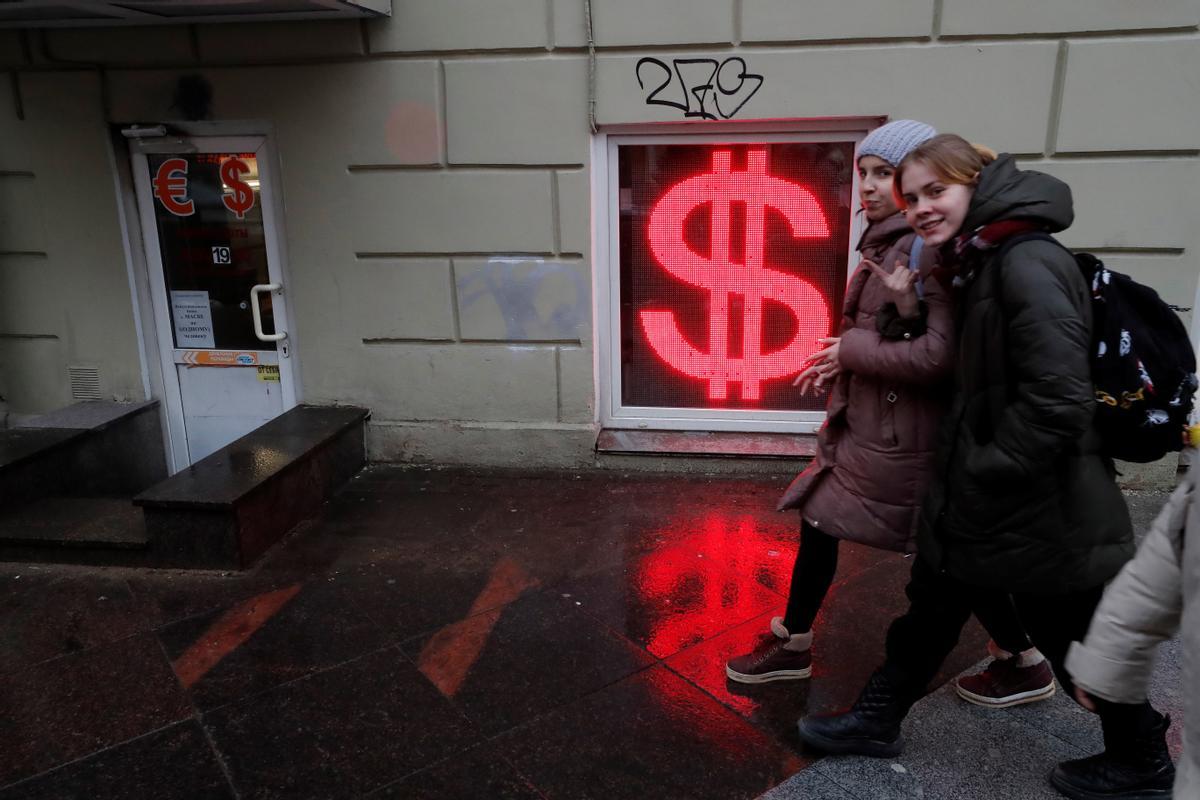 Un grupo de chicas pasan ante una oficina de cambio de divisas en San Petersburgo, este martes.