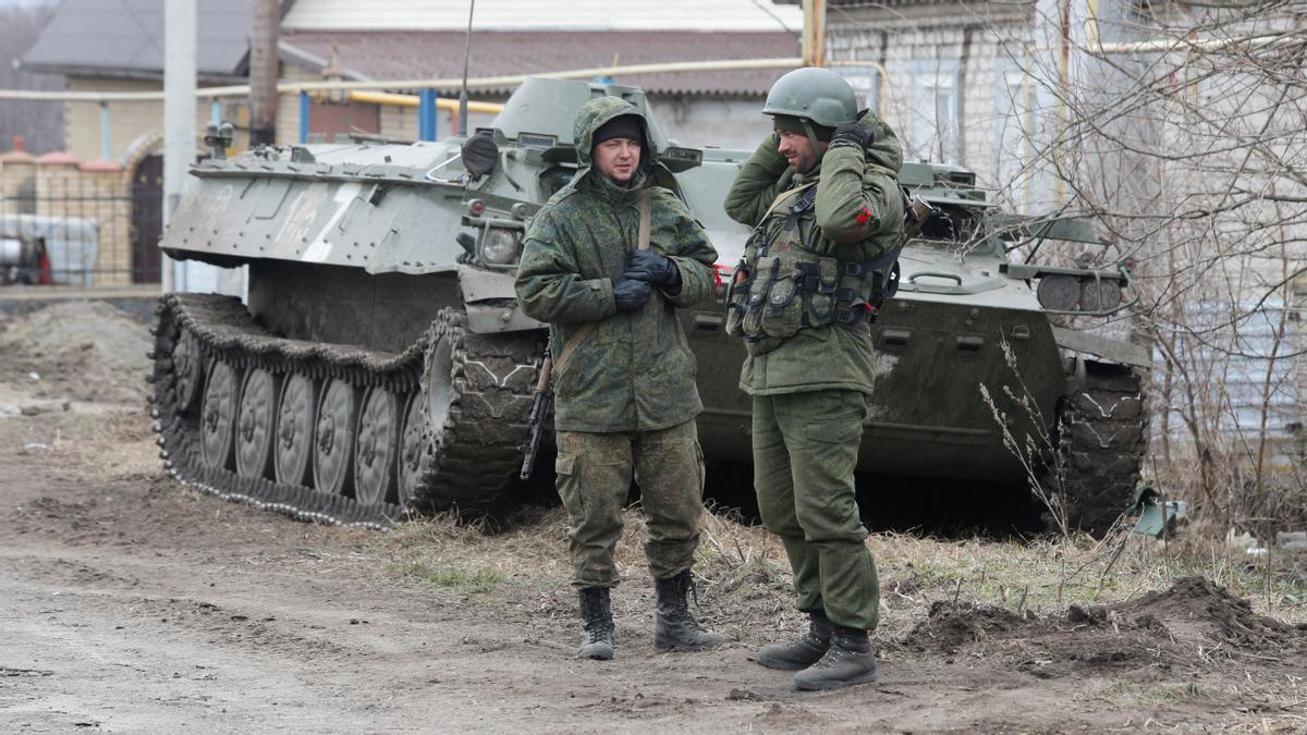Service members of pro-Russian troops in uniforms without insignia stand next to an armoured vehicle in the separatist-controlled settlement of Buhas (Bugas), as Russias invasion of Ukraine continues, in the Donetsk region, Ukraine March 1, 2022. REUTERS/Alexander Ermochenko