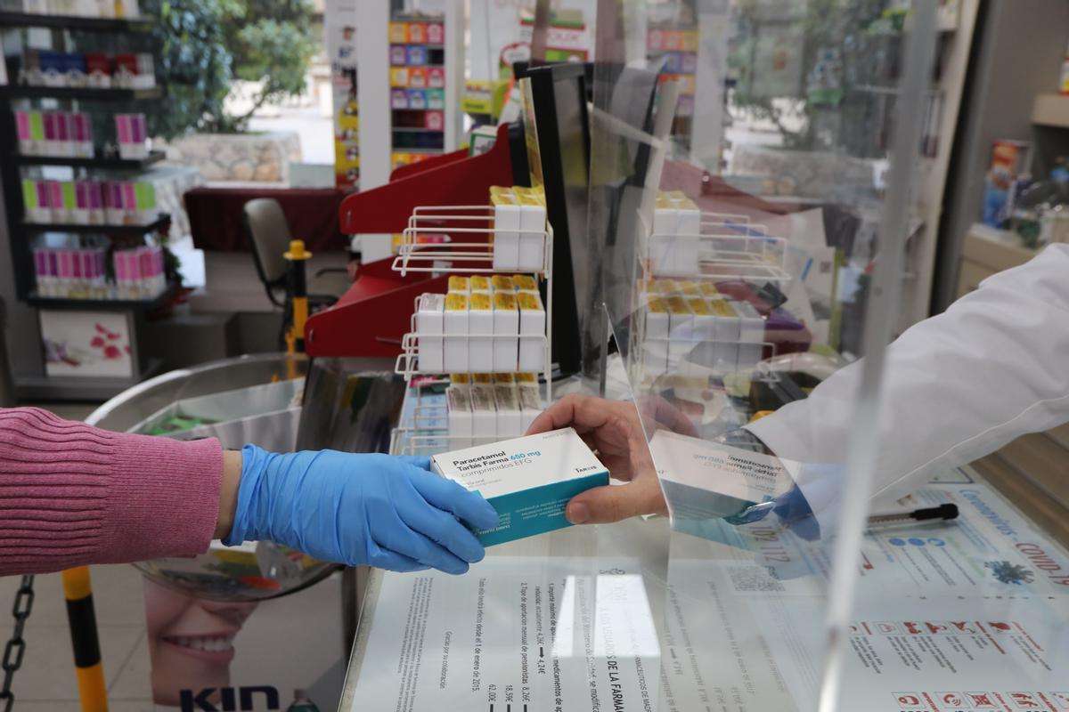 Un farmacéutico vende una caja de paracetamol.