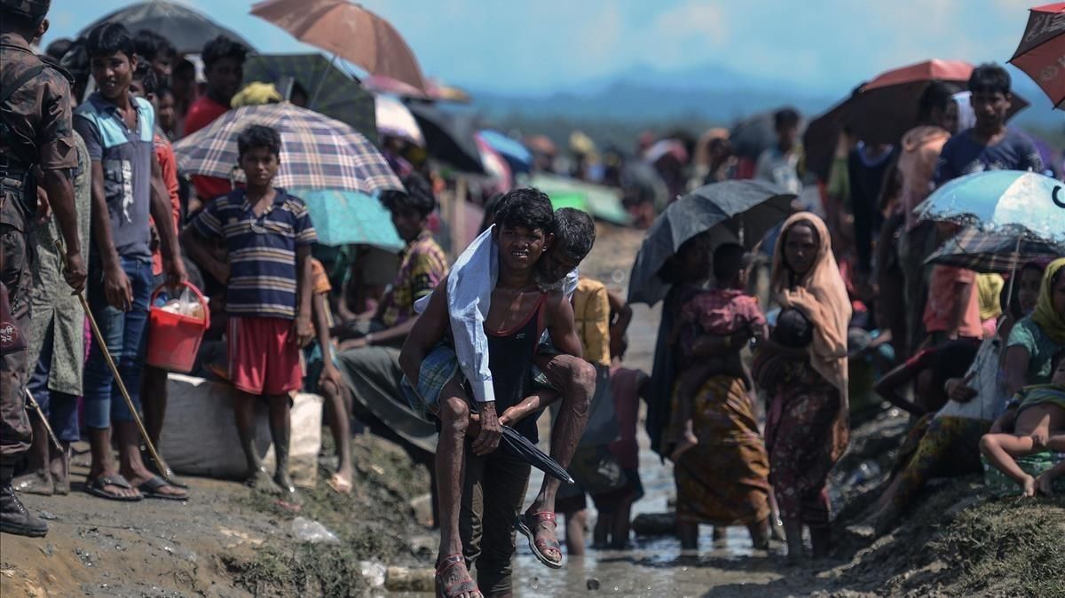 Un refugiado rohinyá lleva a cuestas a un anciano en Bangladés, cerca de la frontera con Birmania. Un refugiado rohinyá lleva a cuestas a un anciano en Bangladés, cerca de la frontera con Birmania.