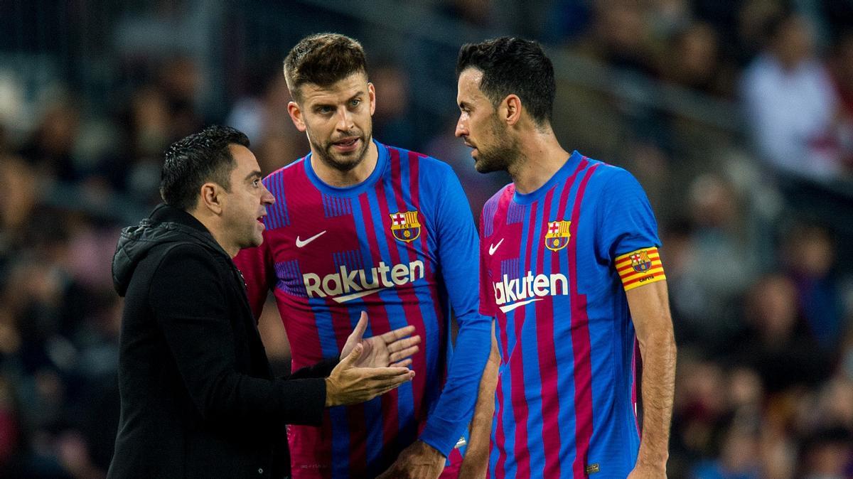 Xavi charla con Piqué y Busquets durante el derbi con el Espanyol en el Camp Nou.