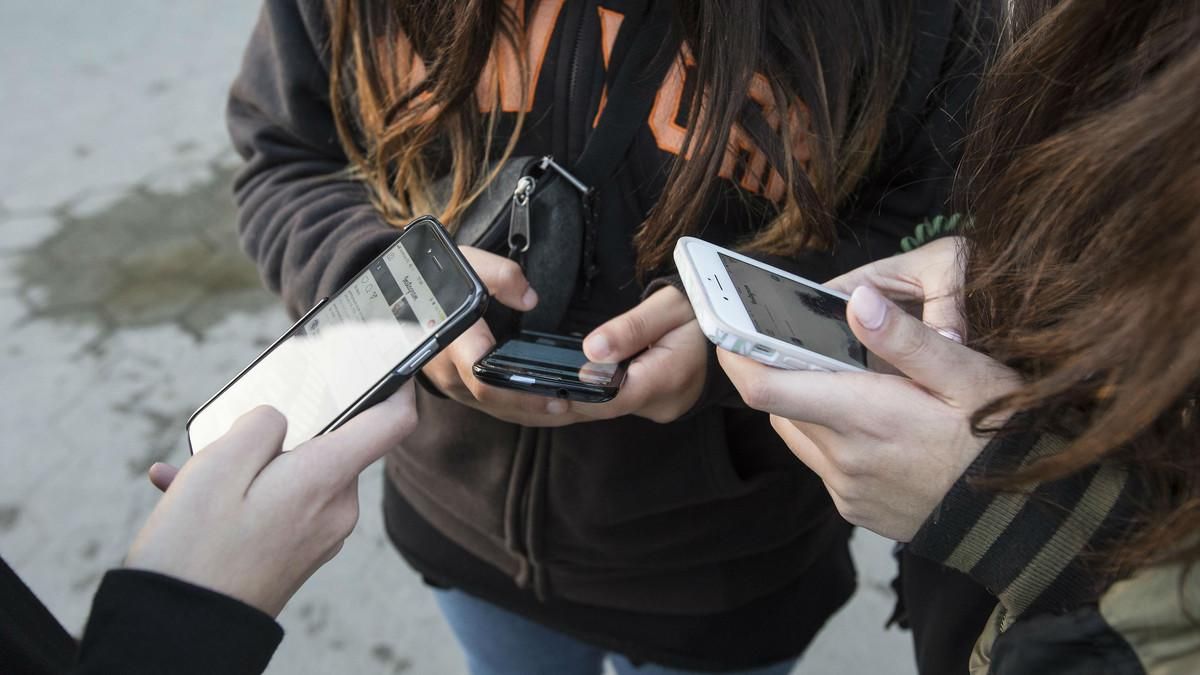 Un grupo de menores consulta su teléfono móvil. Un grupo de menores consulta su teléfono móvil.