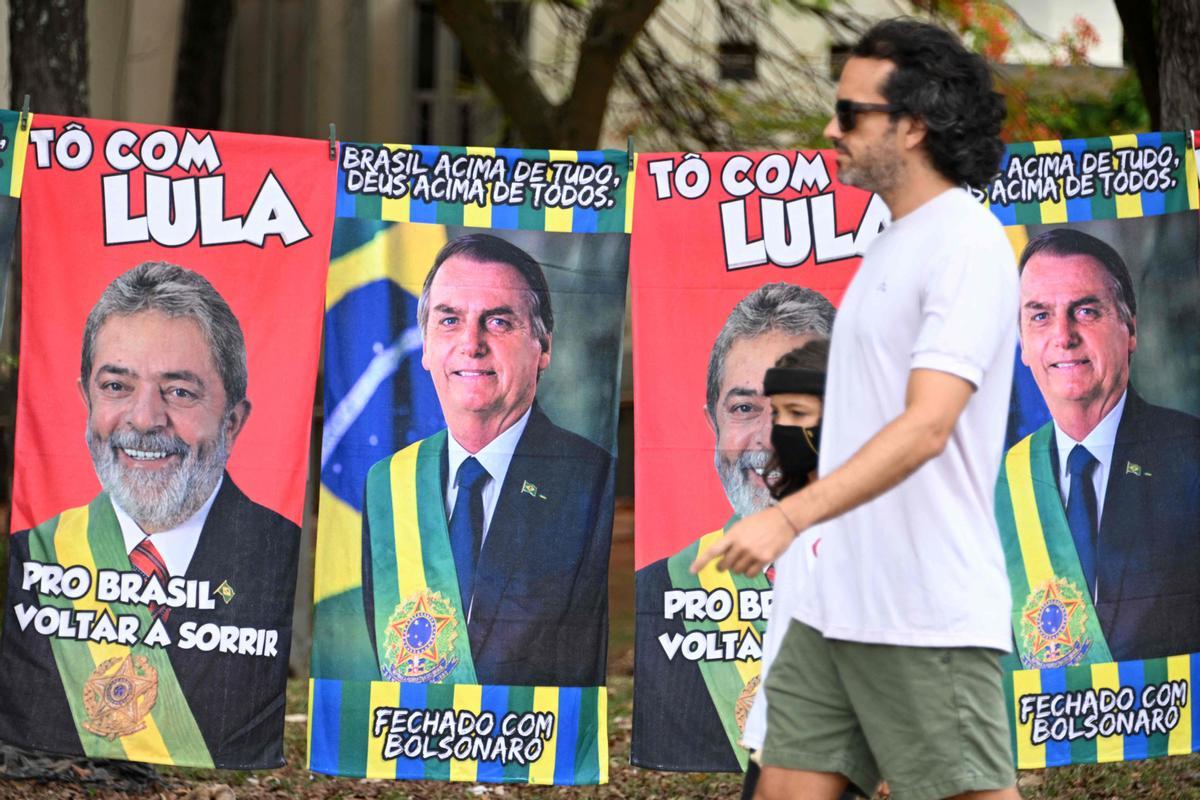 Un hombre camina junto a carteles electorales de Lula y Bolsonaro, en una calle de Brasilia.