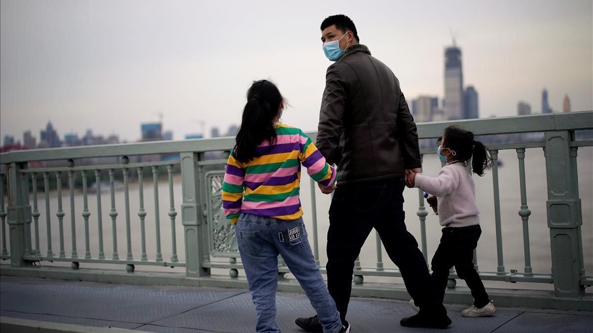 Un adulto y dos niños cruzan el puente de Wuhan, capital de Hubei, en China.
