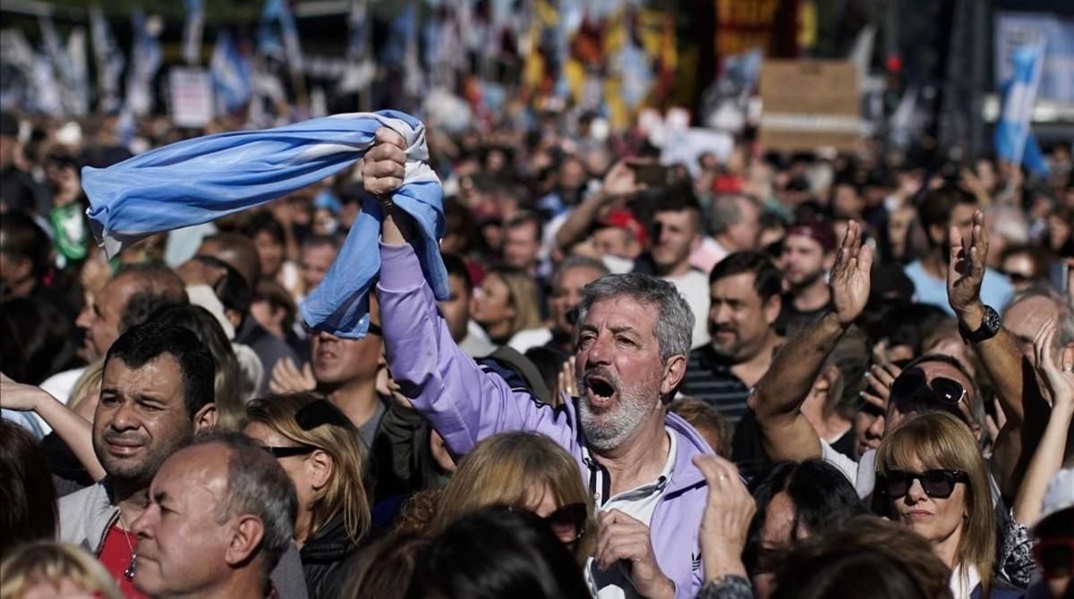 Un hombre empuña la bandera argentina entre la multitud que ha tomado las calles de Buenos Aires para protestar por la situación económica del país. Un hombre empuña la bandera argentina entre la multitud que ha tomado las calles de Buenos Aires para protestar por la situación económica del país.