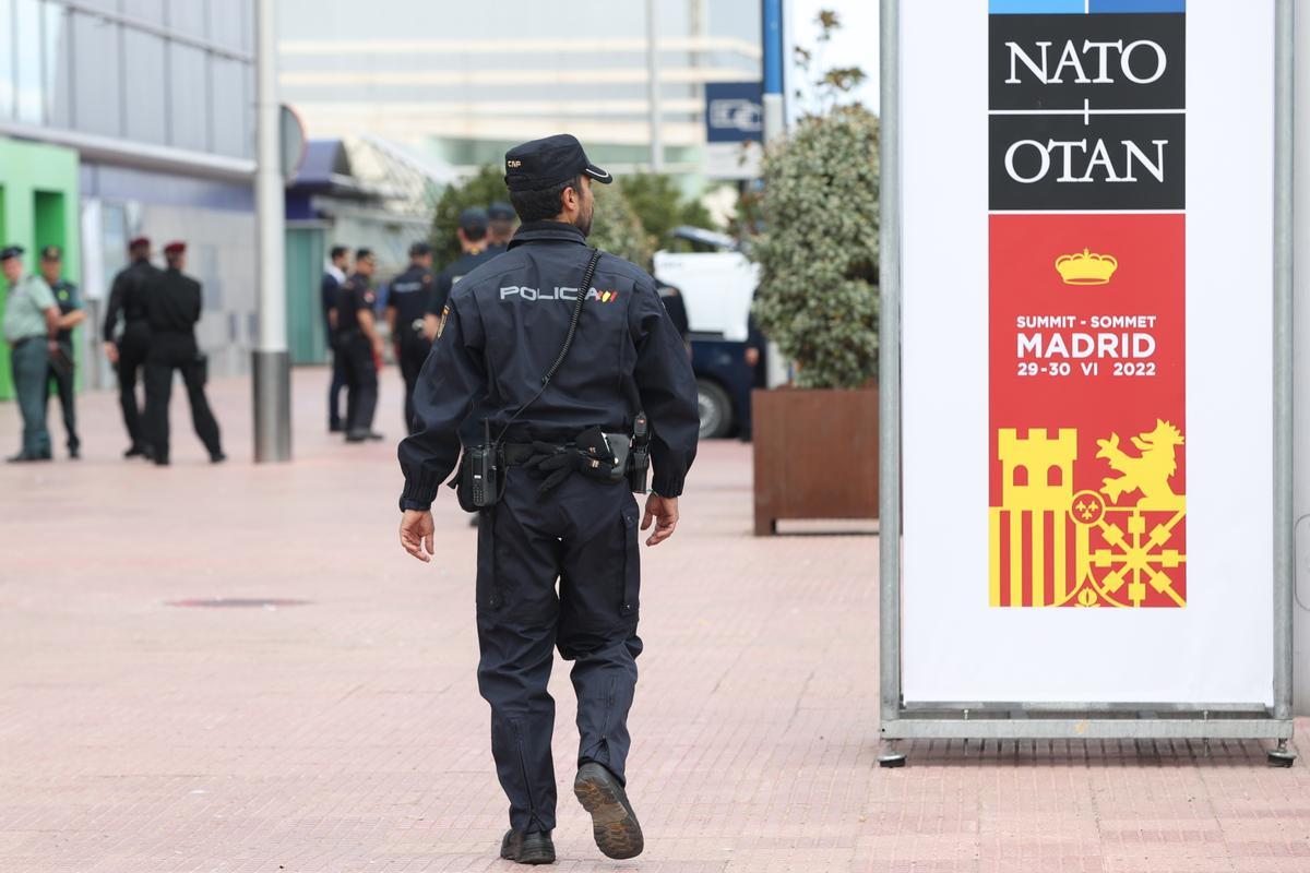 Un policía pasa junto a un cartel de la cumbre de la OTAN en Madrid.
