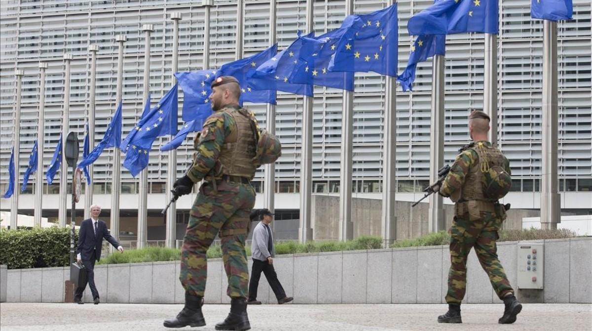 Soldados belgas patrullan junto a las banderas de la UE que ondean a media asta por el atentado de Manchester, el 23 de mayo, en Bruselas. 