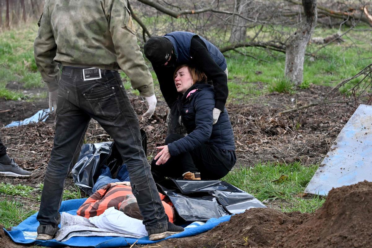 La esposa de un civil reacciona después de que su cuerpo fuera exhumado de una tumba poco profunda cerca de su casa en el pueblo de Andriivka, región de Kiev, el 11 de abril de 2022. (Foto de Sergei SUPINSKY / AFP)