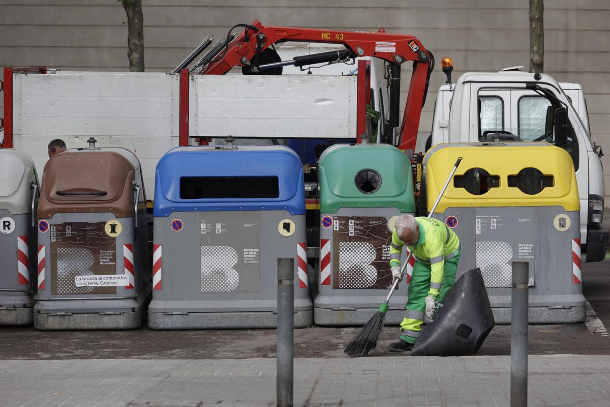Un operario de la limpieza de Barcelona delante de unos contenedores y un camión de la basura, en el distrito de Nou Barris.
