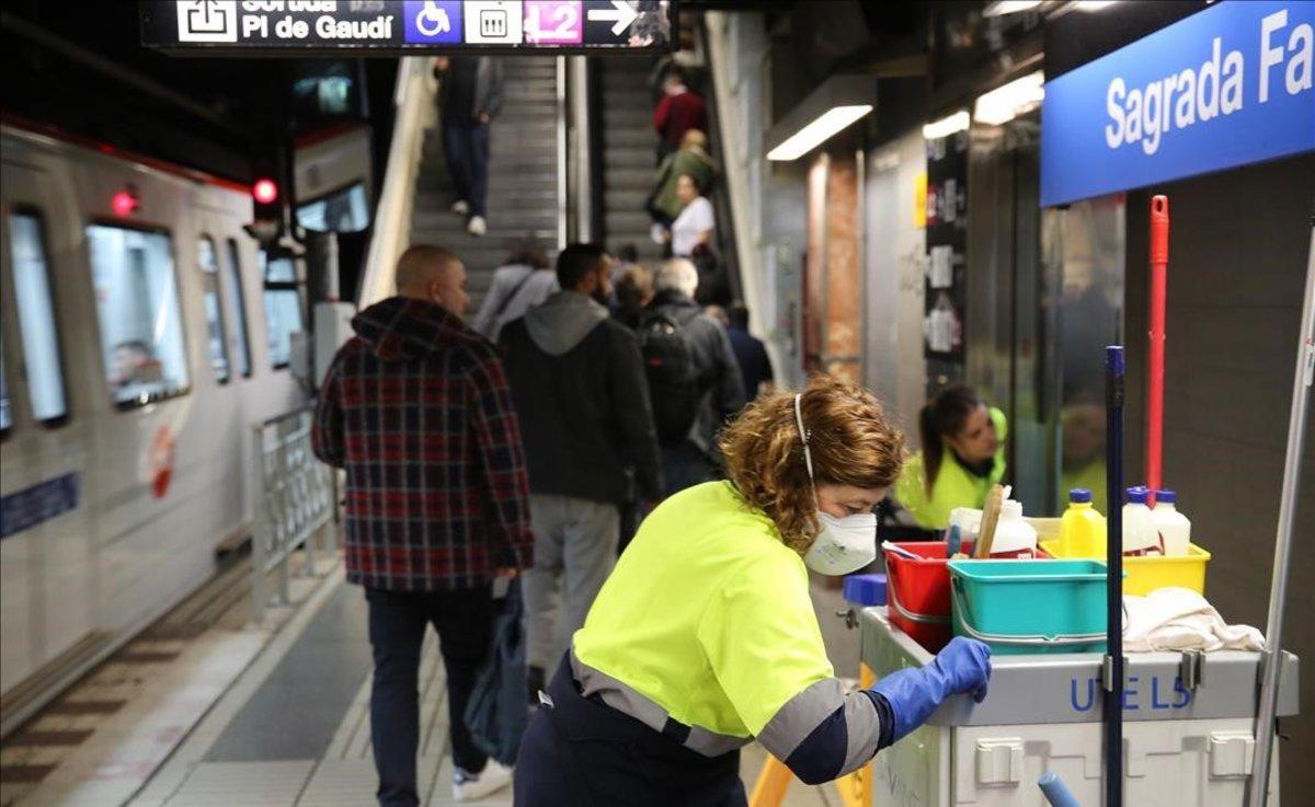 Una operaria de la limpiea con mascarllla trabaja en la estación de metro de Sagrada Família.