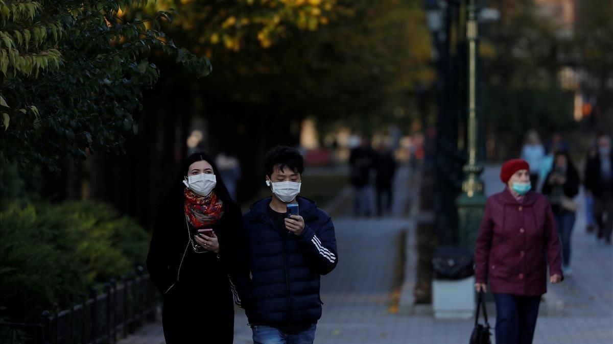 Varias personas con mascarilla pasena por un parque de Moscú, este martes. Varias personas con mascarilla pasena por un parque de Moscú, este martes.