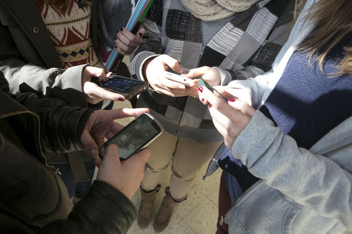 Unos jóvenes consultan sus móviles. Unos jóvenes consultan sus móviles.