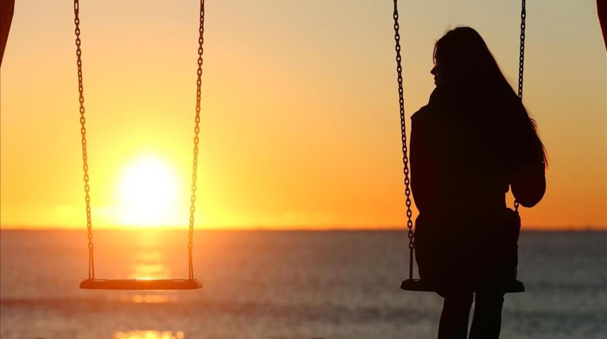 Una joven contempla la puesta de sol en una playa.