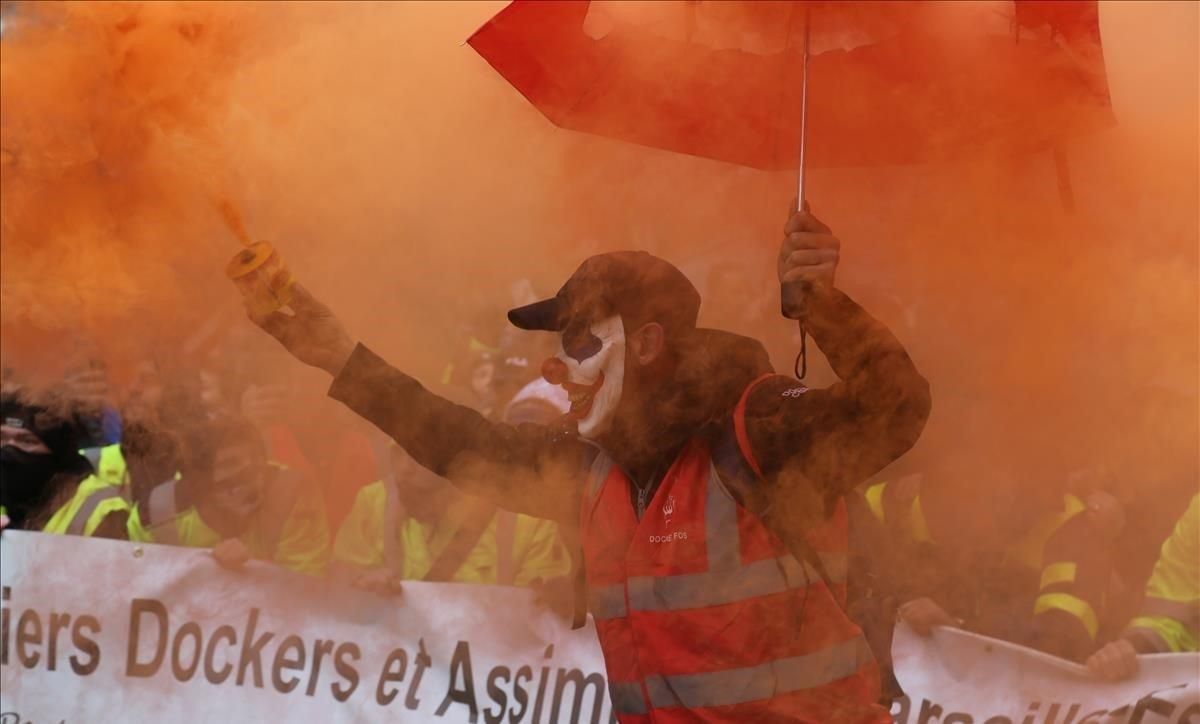 Un manifestante enciende una antorcha de humo durante la huelga contra las reformas del sistema de pensiones del Gobierno francés, este viernes, en Marsella. Un manifestante enciende una antorcha de humo durante la huelga contra las reformas del sistema de pensiones del Gobierno francés, este viernes, en Marsella.