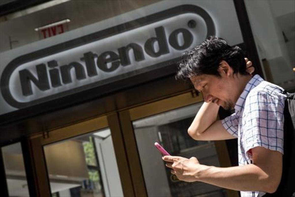 Un hombre juega al Pokémon Go con su móvil frente a la sede de Nintendo en Nueva York, el lunes. Un hombre juega al Pokémon Go con su móvil frente a la sede de Nintendo en Nueva York, el lunes.