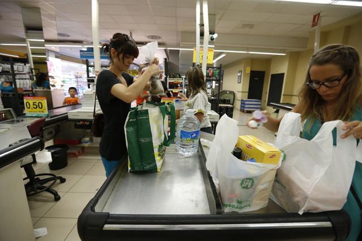 Una clienta con una bolsa ecológica y otra, con bolsas de plástico, en un supermercado. Una clienta con una bolsa ecológica y otra, con bolsas de plástico, en un supermercado.