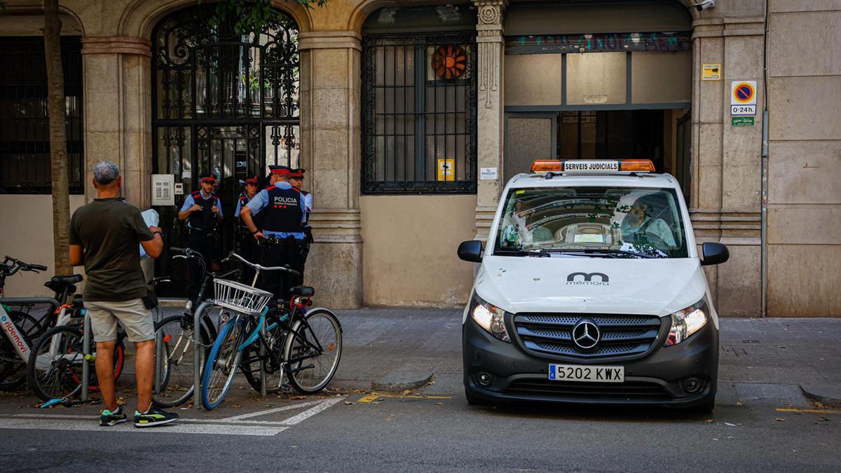 Muere un niño al precipitarse por un patio de luces en el Eixample de Barcelona. En la foto, un coche de los servicios funerarios retira el cuerpo del pequeño.