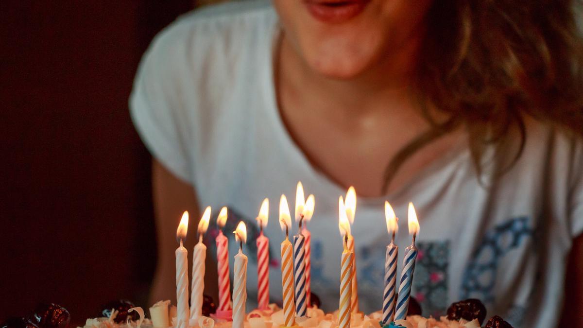 Una mujer sopla velas en un pastel de cumpleaños