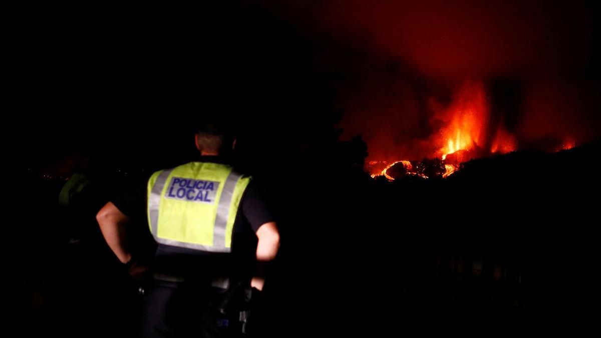 Un agente de la policía local sigue la erupción del volcán de La Palma en la distancia. Un agente de la policía local sigue la erupción del volcán de La Palma en la distancia.