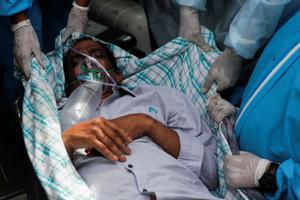 Un enfermo de covid es evacuado del hospital indio incendiado este viernes. 