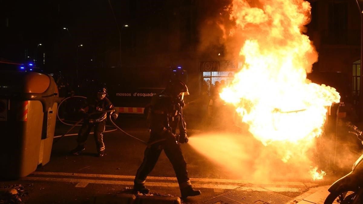 Bomberos apagan un contenedor en llamas en las protestas de los manifestantes contra un acto de Vox. Bomberos apagan un contenedor en llamas en las protestas de los manifestantes contra un acto de Vox.
