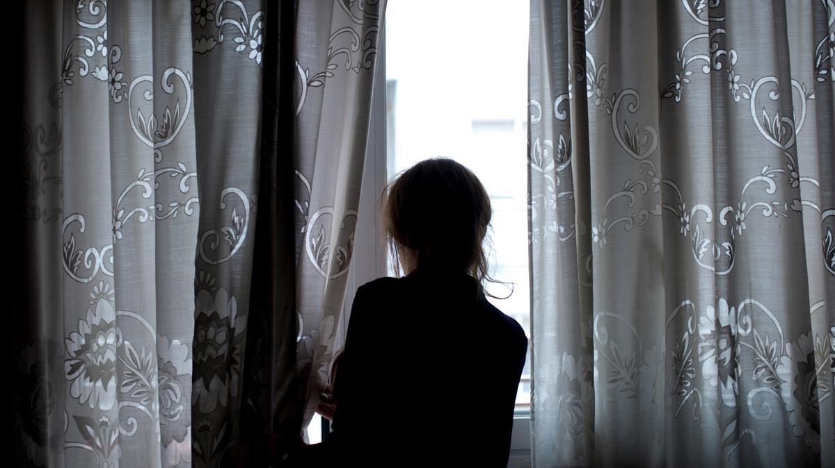 Una mujer observa a través de la ventana de su vivienda en Ourense durante el confinamiento, el pasado 19 de abril.