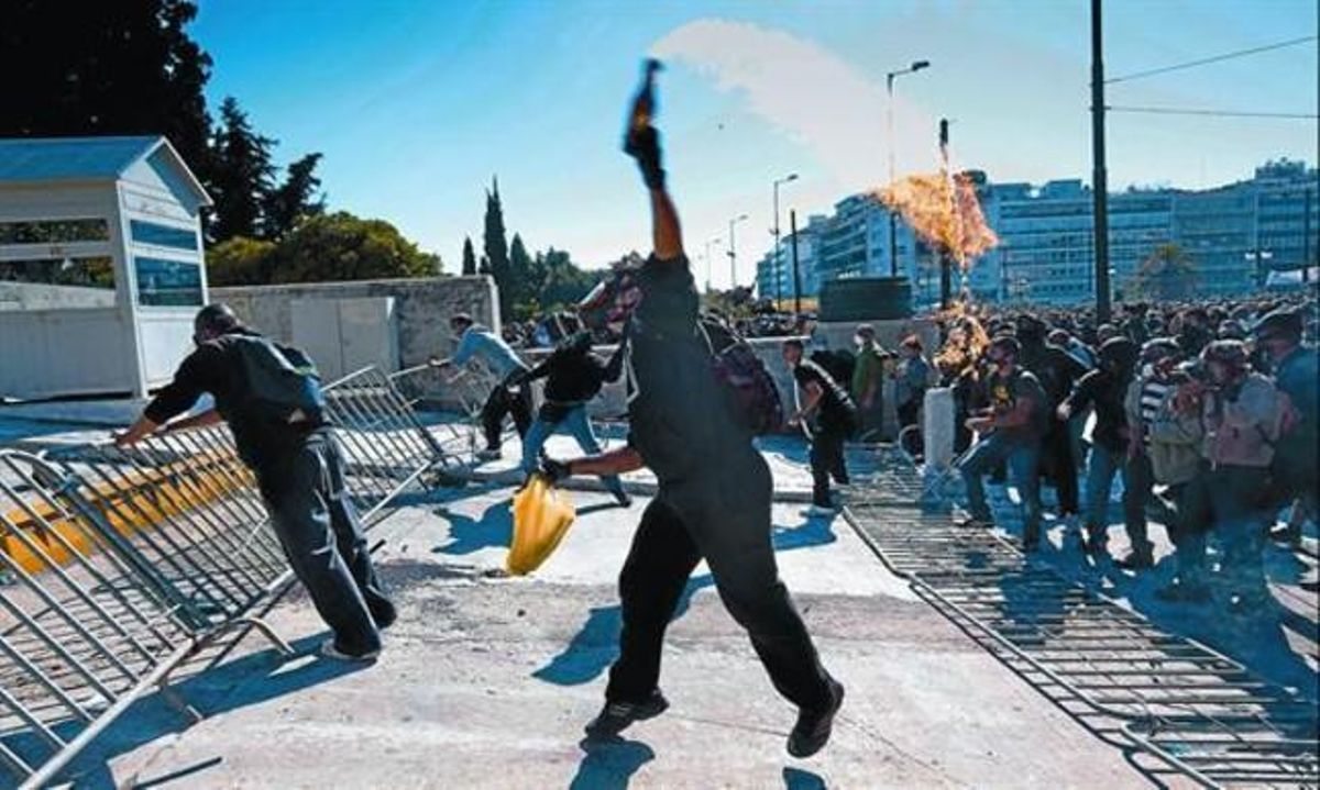 Un activista lanza un coctel molotov al final de la manifestaciónde Atenas, ayer. Un activista lanza un coctel molotov al final de la manifestaciónde Atenas, ayer.