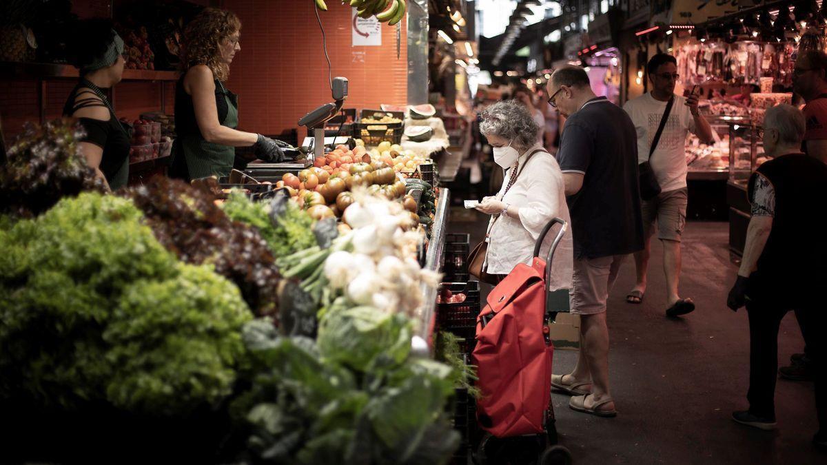 Una mujer consulta su lista de la compra en el mercado de la Boqueria