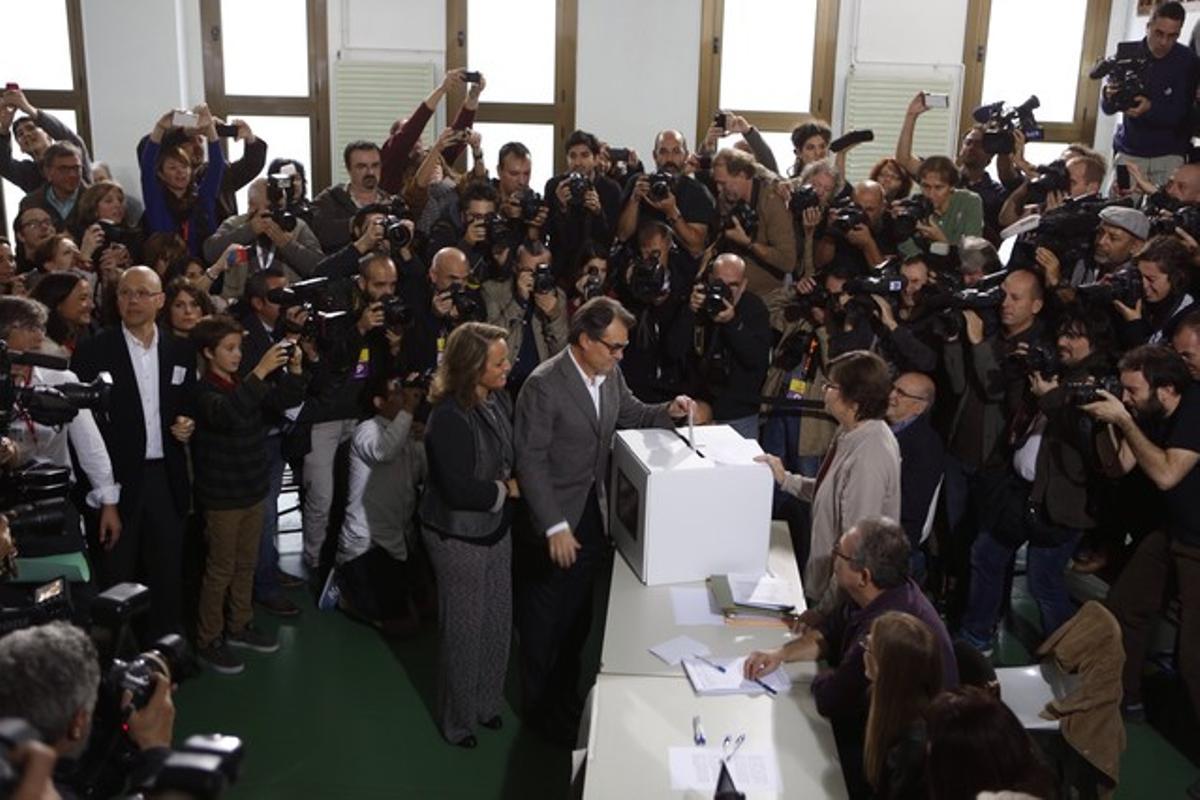 Artur Mas vota junto a su esposa, rodeado de cámaras y fotógrafos.