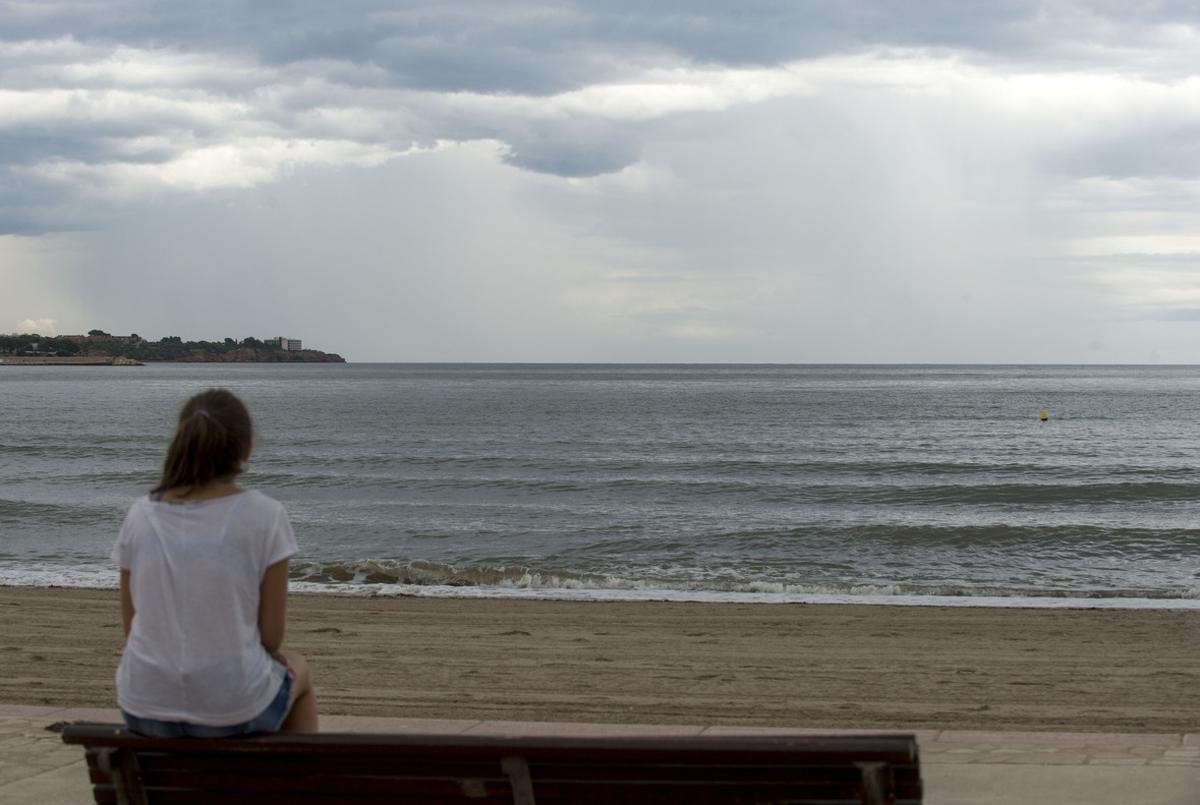 Una mujer mira el cielo que amenaza lluvia en la playa del Arenal, en LAmpolla (Baix Ebre).