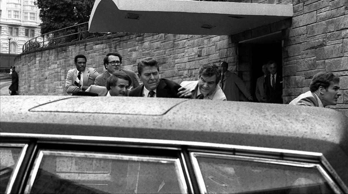 Reagan es introducido por sus escoltas en el coche presidencial tras los disparos de Hinckley. Reagan es introducido por sus escoltas en el coche presidencial tras los disparos de Hinckley.