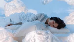 Simulación de una mujer durmiendo entre algodones o nubes blancas.