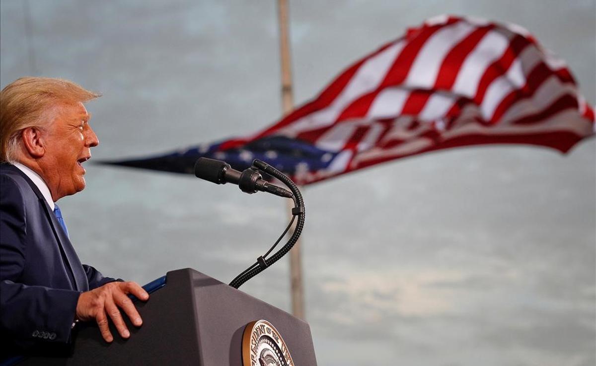 Donald Trump habla, con una bandera detrás de él, durante un acto de campaña en el aeropuerto de Cecil, en Jacksonville, Florida, el 24 de septiembre del 2020.