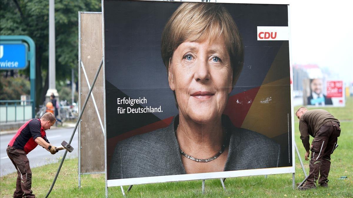 Retirada de un cartel electoral de Angela Merkel en Berlín.