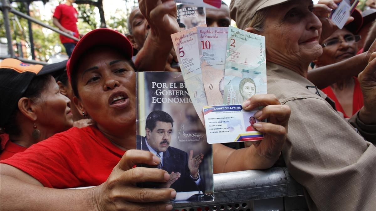 Una seguidora de Maduro muestra la nueva moneda venezolana.