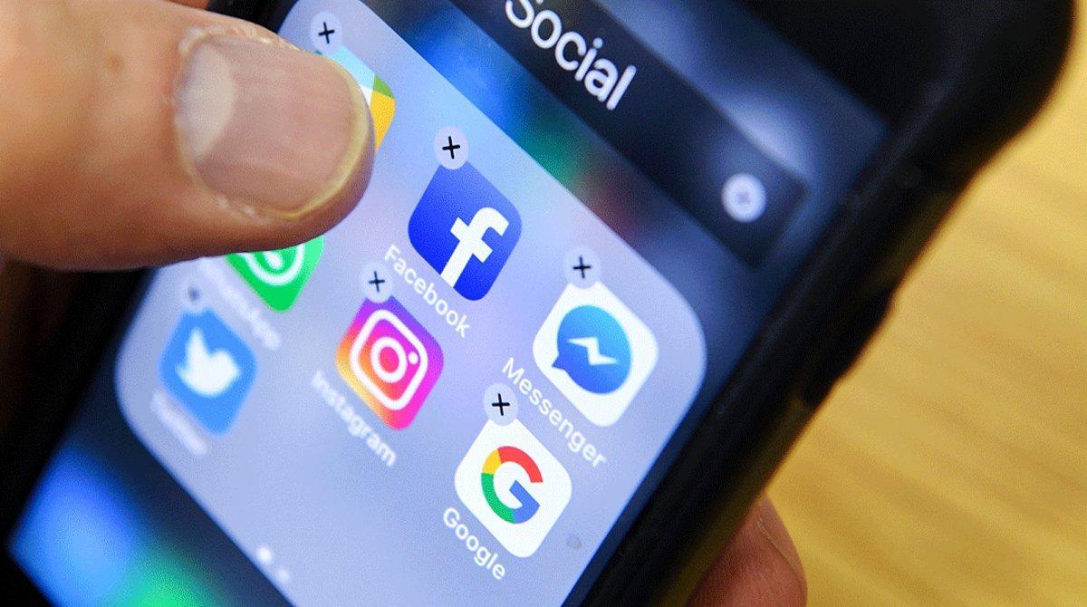 Un hombre organiza los iconos de varias redes sociales como Facebook, Instagram y Twitter en la pantalla de su móvil.