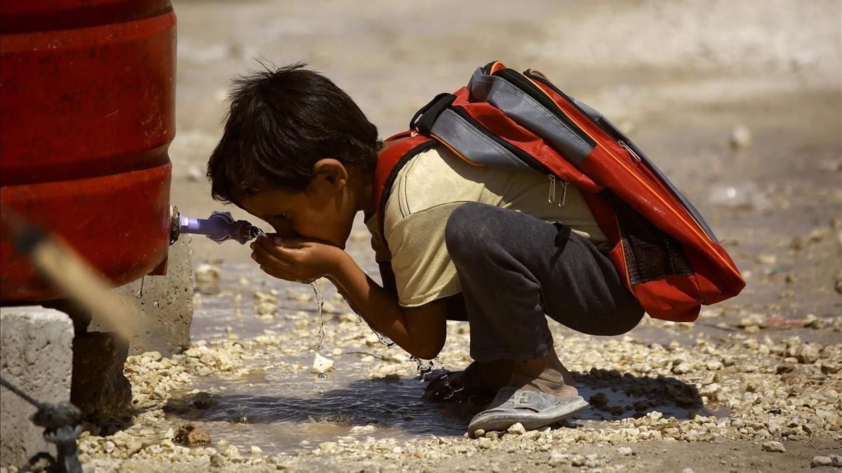 Un niño sirio, desplazado por la violencia del Estado Islámico, bebe agua antes de empezar el primer día de escuela en un campo para desplazados internos en Ain Issa, Siria. Un niño sirio, desplazado por la violencia del Estado Islámico, bebe agua antes de empezar el primer día de escuela en un campo para desplazados internos en Ain Issa, Siria.