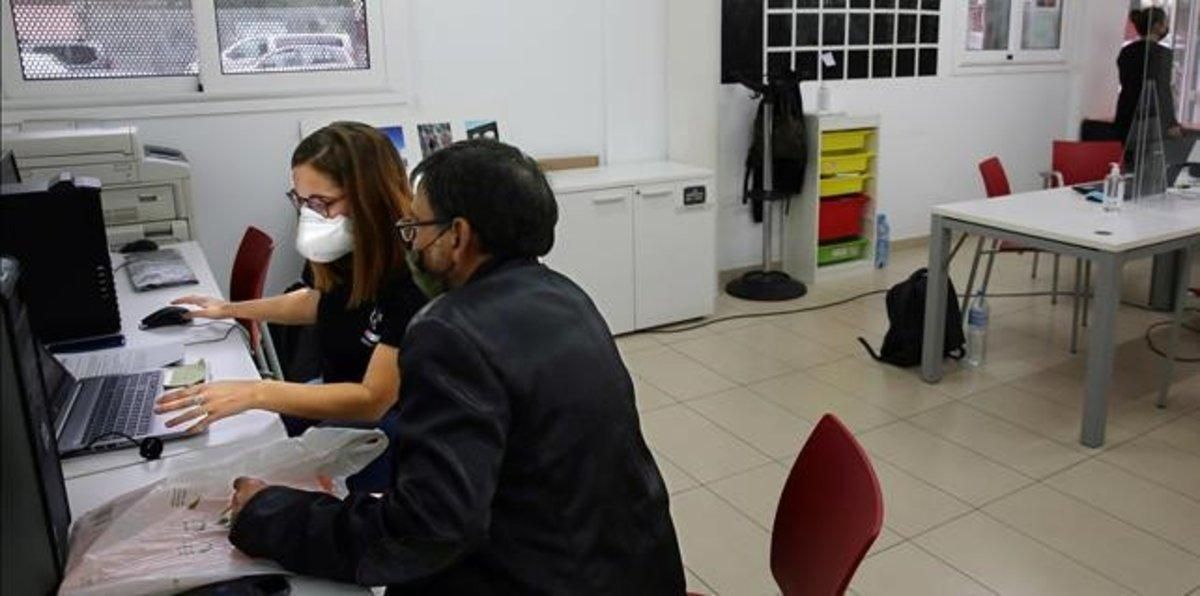 Una agente de apoyo digital del ayuntamiento junto a un usuario, en el casal del barrio Besòs-Maresme. Una agente de apoyo digital del ayuntamiento junto a un usuario, en el casal del barrio Besòs-Maresme.