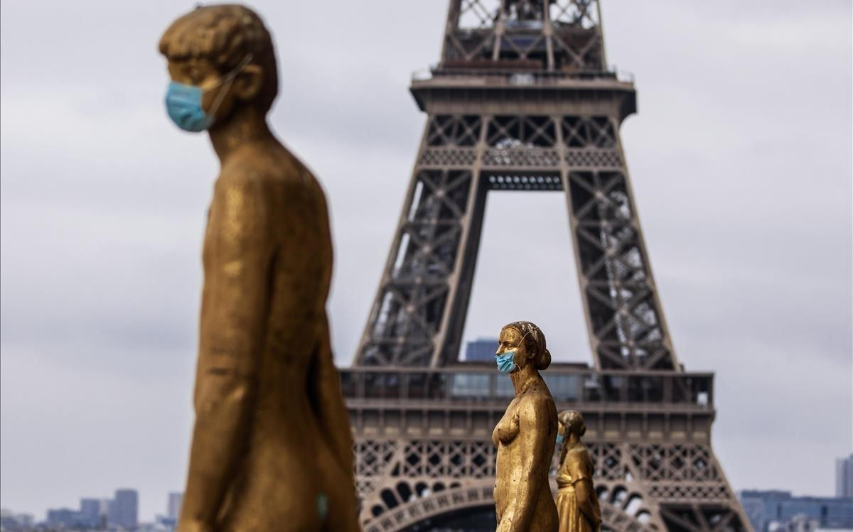 Las estatuas doradas de la explanada de Trocadero, frente a la Torre Eiffel, están cubiertas con máscaras protectoras en París.