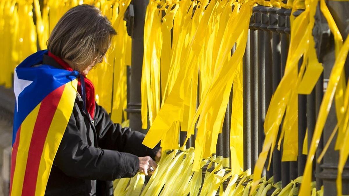 Una mujer coloca lazos amarillos en una verja en el parque de la Ciutadella en Barcelona, en una foto de archivo