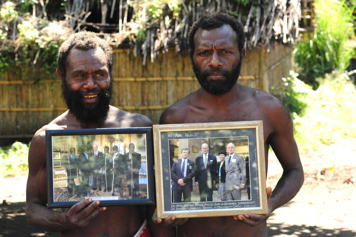 Dos miembros de una tribu en Yaohnanen muestran fotos enmarcadas de su visita en 2007 con el Príncipe Felipe de Edimburgo, su dios Dos miembros de una tribu en Yaohnanen muestran fotos enmarcadas de su visita en 2007 con el Príncipe Felipe de Edimburgo, su dios